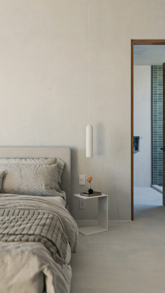 Detalle de recámara minimalista con buró metálico blanco, lámpara colgante y vista hacia el baño interior